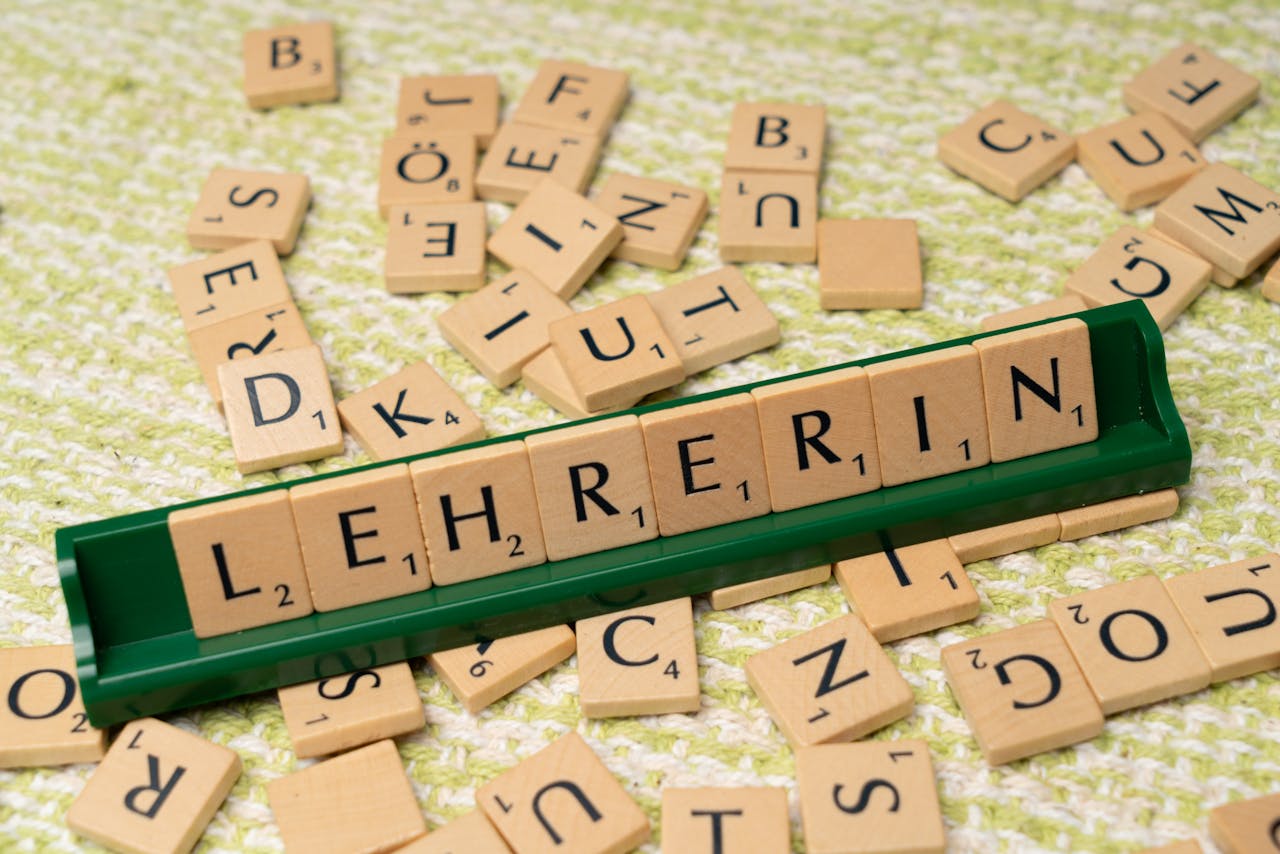Services Wooden Scrabble tiles spelling 'Lehrerin' on a green holder, scattered on a textured surface.
